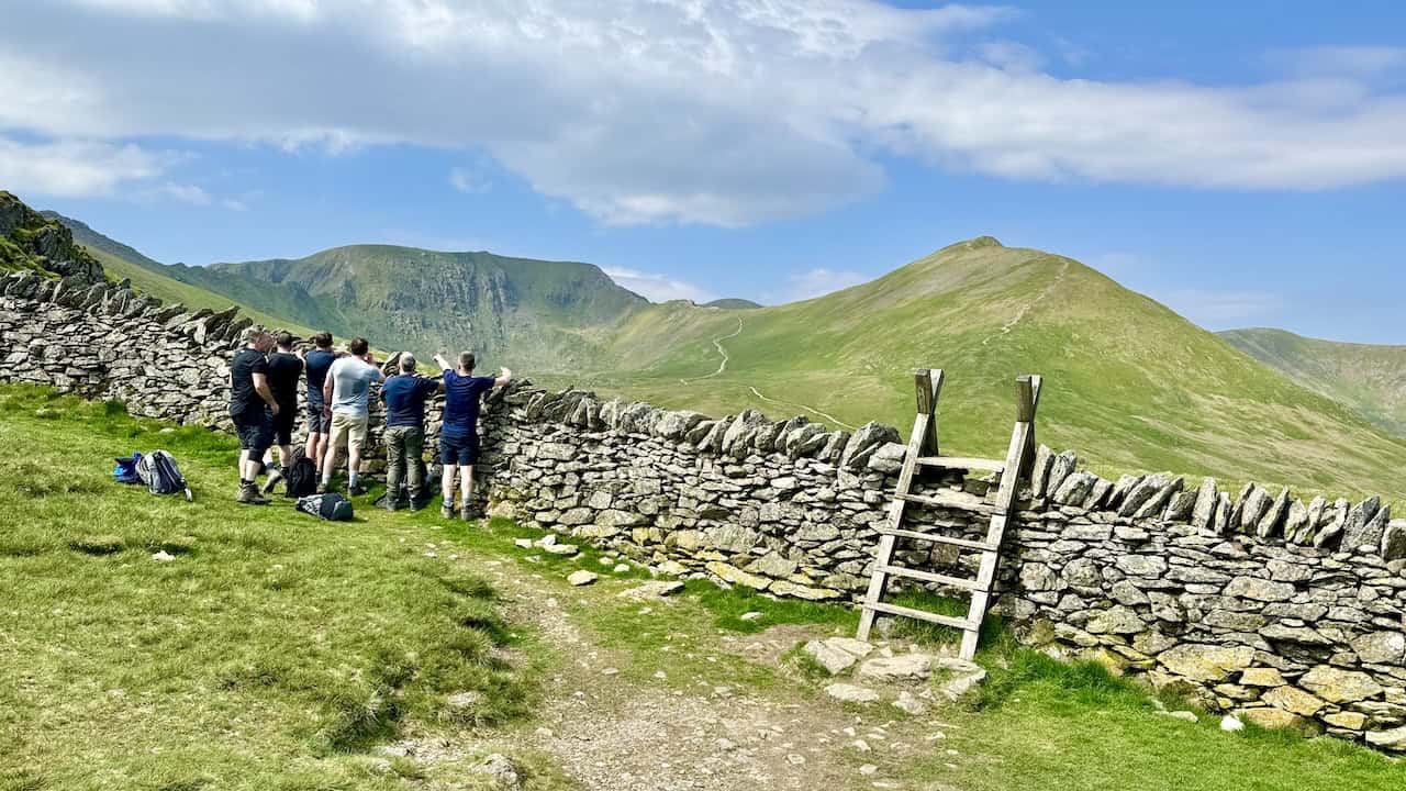 Upon reaching Hole-in-the-Wall, we are greeted by a captivating view of Catstye Cam on the right and Helvellyn on the left. Walkers gather to discuss their routes, with Striding Edge appearing to the left and the path to Swirral Edge also visible, though not our chosen path today.