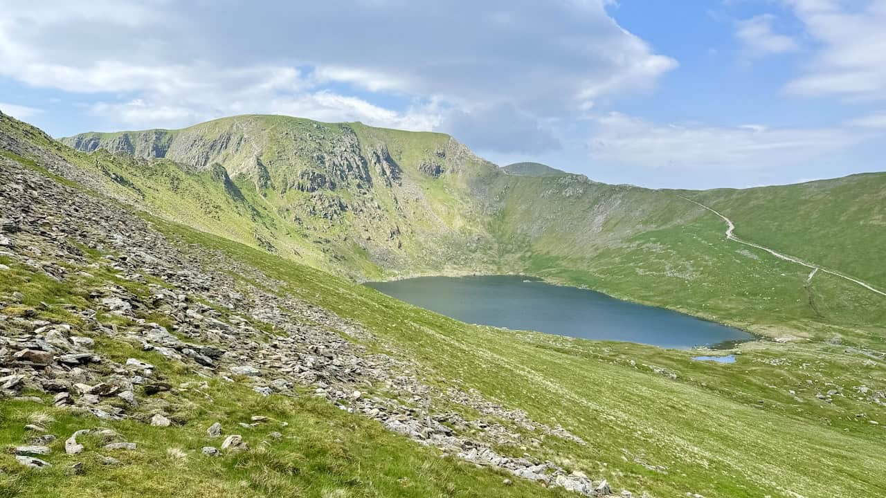 Approaching Low Spying How, we catch our first glimpse of Red Tarn, nestled between Striding Edge and Swirral Edge below Helvellyn. This view is a highlight of the Helvellyn via Striding Edge walk.