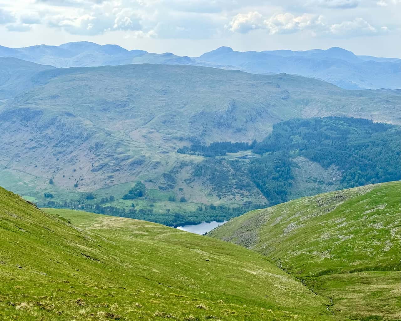 The view west from above Swallow Scarth between Helvellyn and Nethermost Pike reveals Thirlmere Reservoir, with Harrop Tarn and Ullscarf in the distance.