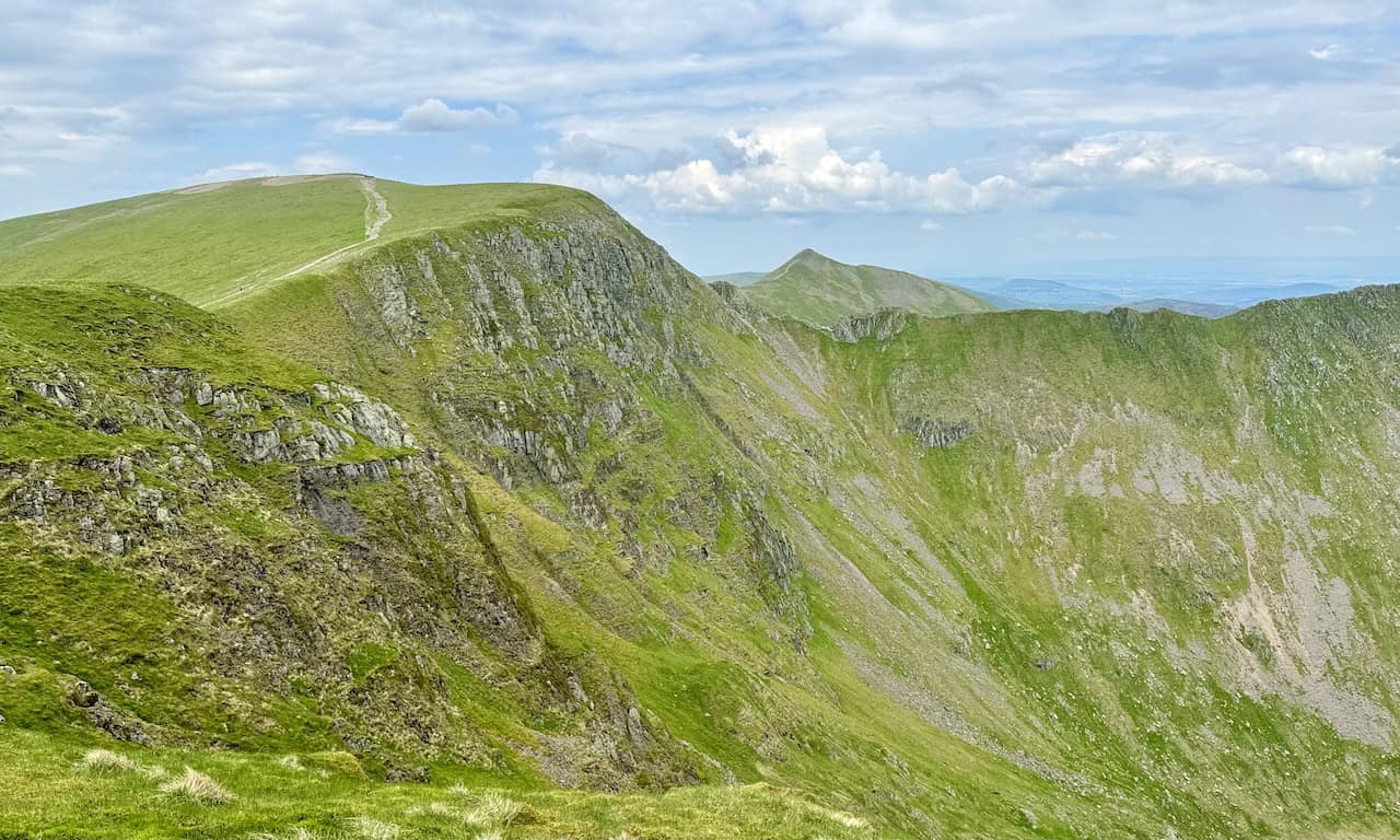 Looking back, we see our route from Helvellyn. Striding Edge is visible, and Catstye Cam peaks out behind the ridge. The rocky outcrops of Swallow Scarth and Lad Crag create an impressive scene.