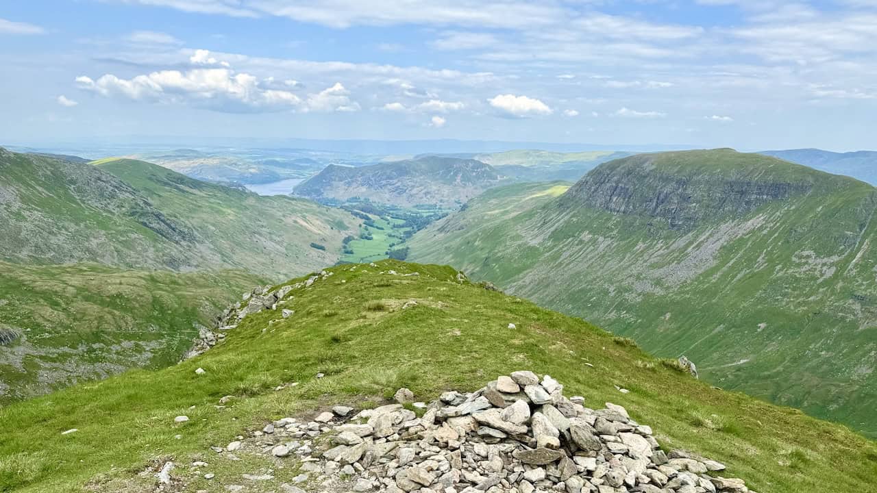 The view north-east from the cairns at the top of Dollywaggon Pike shows St Sunday Crag impressively on the right. Gullies running down the side of the mountain, named West Chockstone Gully, Y Gully, and East Chockstone Gully, are visible. Place Fell and Ullswater are easily seen, with Birkhouse Moor to the left.