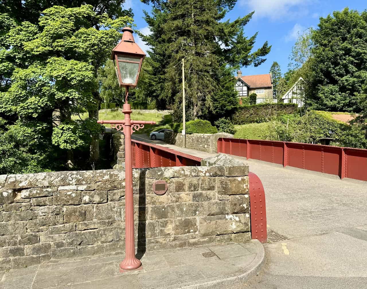 The bridge crossing Eller Beck near the railway station with a vintage-style lamp post. The plaque commemorates Frances Johnson, who enjoyed visiting Goathland with her husband, John.
