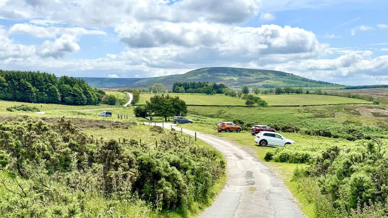 Eventually, High Lane (Track) reaches a small car parking area and then a minor road. It’s straight on along the road to Chequers. The hill in the background is called Black Hambleton, which reaches 400 metres.