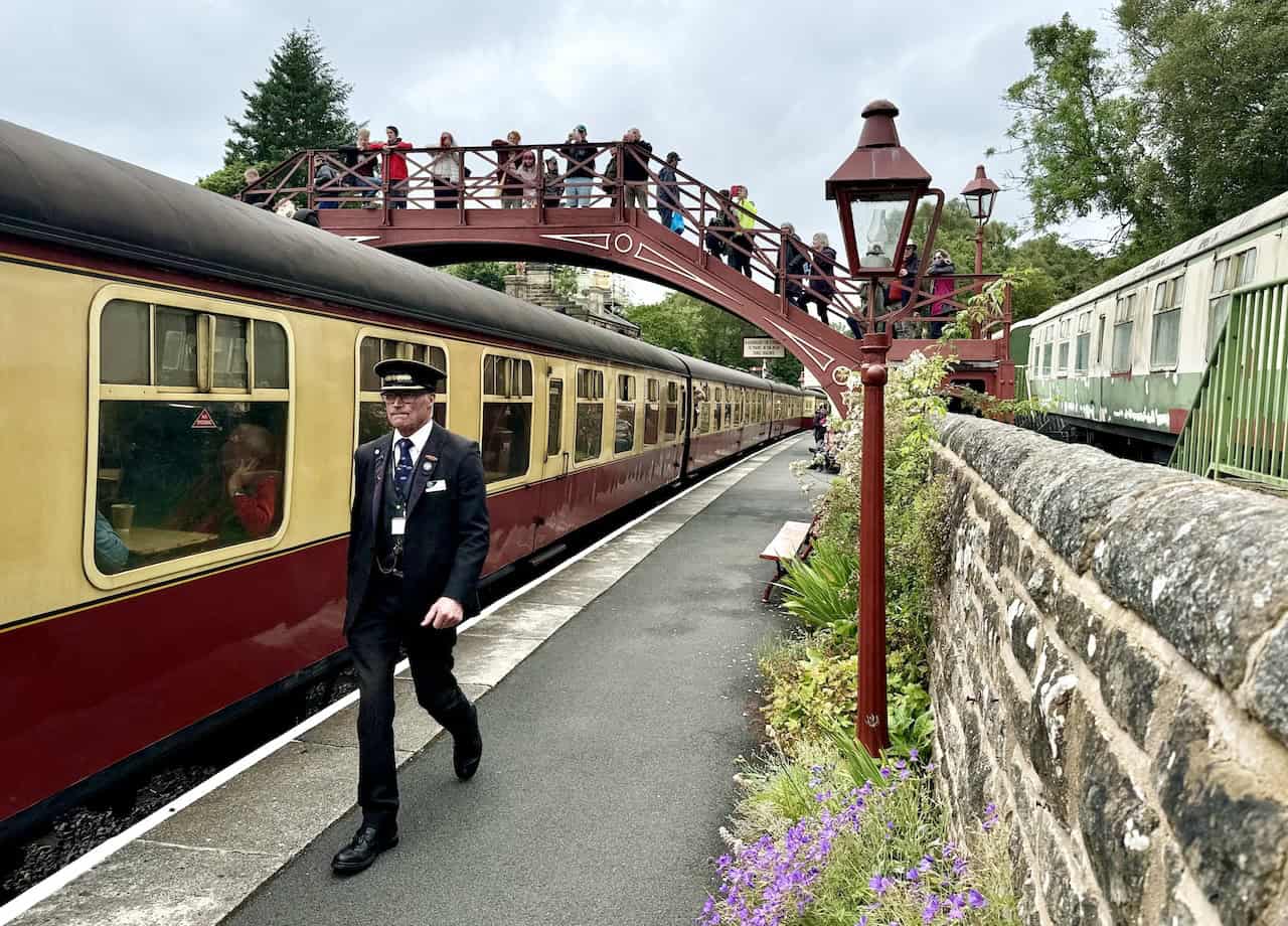 Goathland Railway Station with a steam train pulling into the station. The station opened on 1 July 1865 and is part of the North Yorkshire Moors Railway, a heritage railway. It is known for its appearances in Heartbeat and Harry Potter and the Philosopher’s Stone.