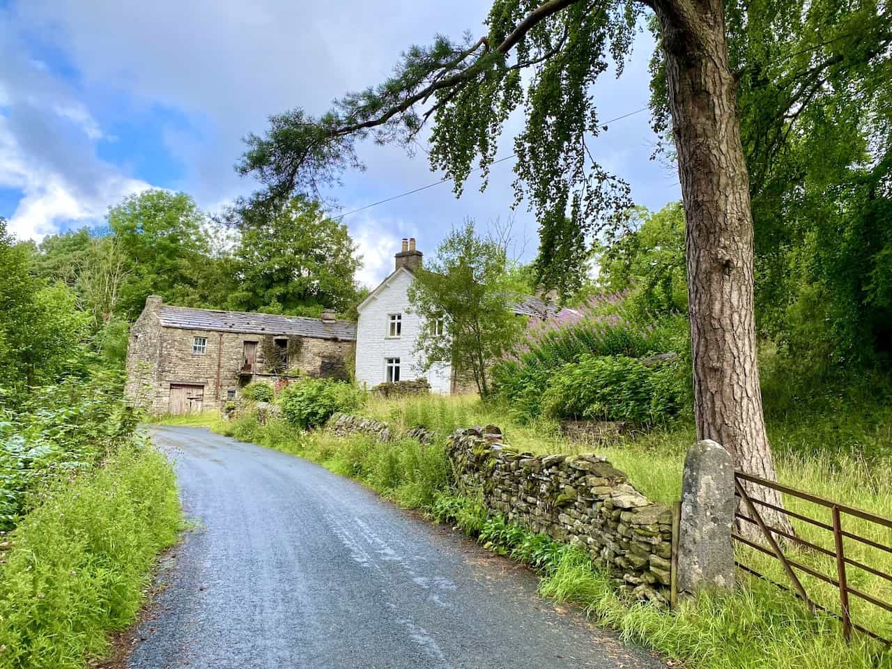 Historic stone farm buildings near Stone House, set against the backdrop of the quiet road through the Dentdale valley, part of the Dentdale walk.