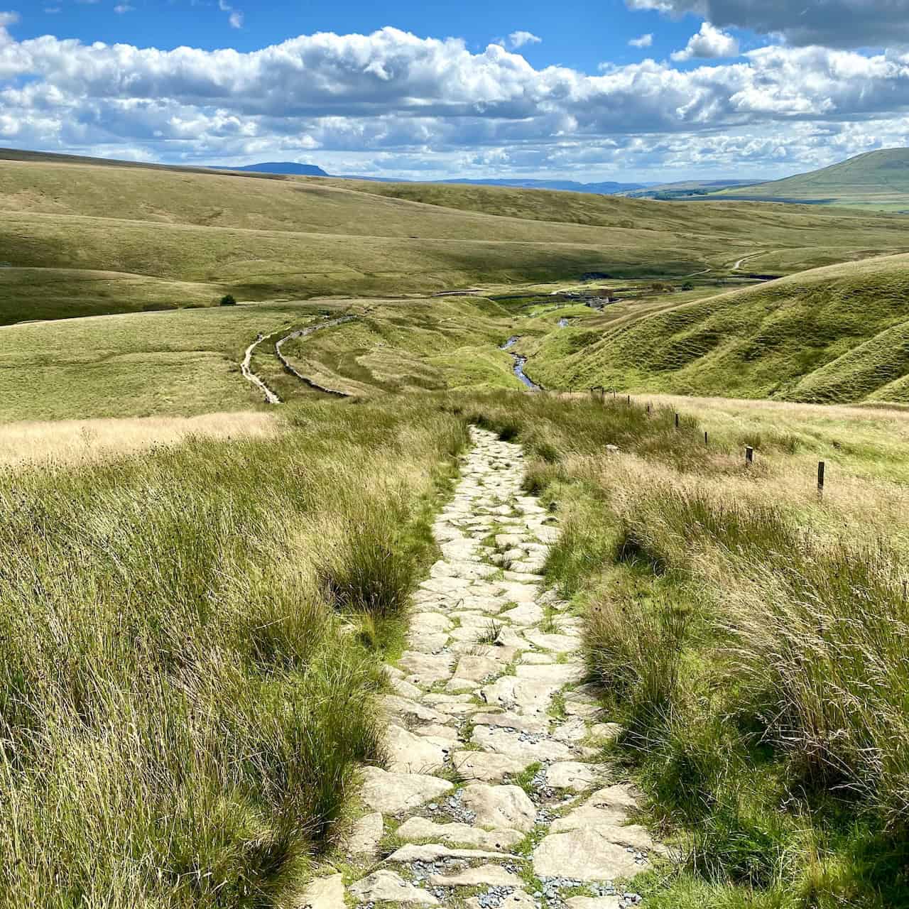 The well-maintained Dales High Way path leading down to the aqueduct near Smithy Hill, crucial for the Yorkshire Three Peaks Challenge.