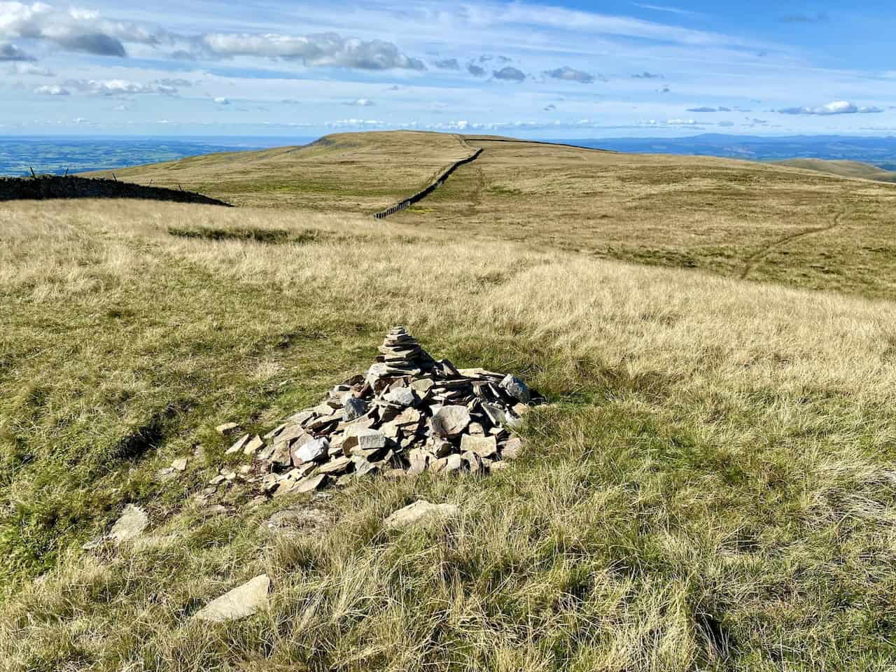 A guiding cairn located 200 metres west of the Great Coum summit, with Crag Hill visible in the background, marking the next stage of the journey.
