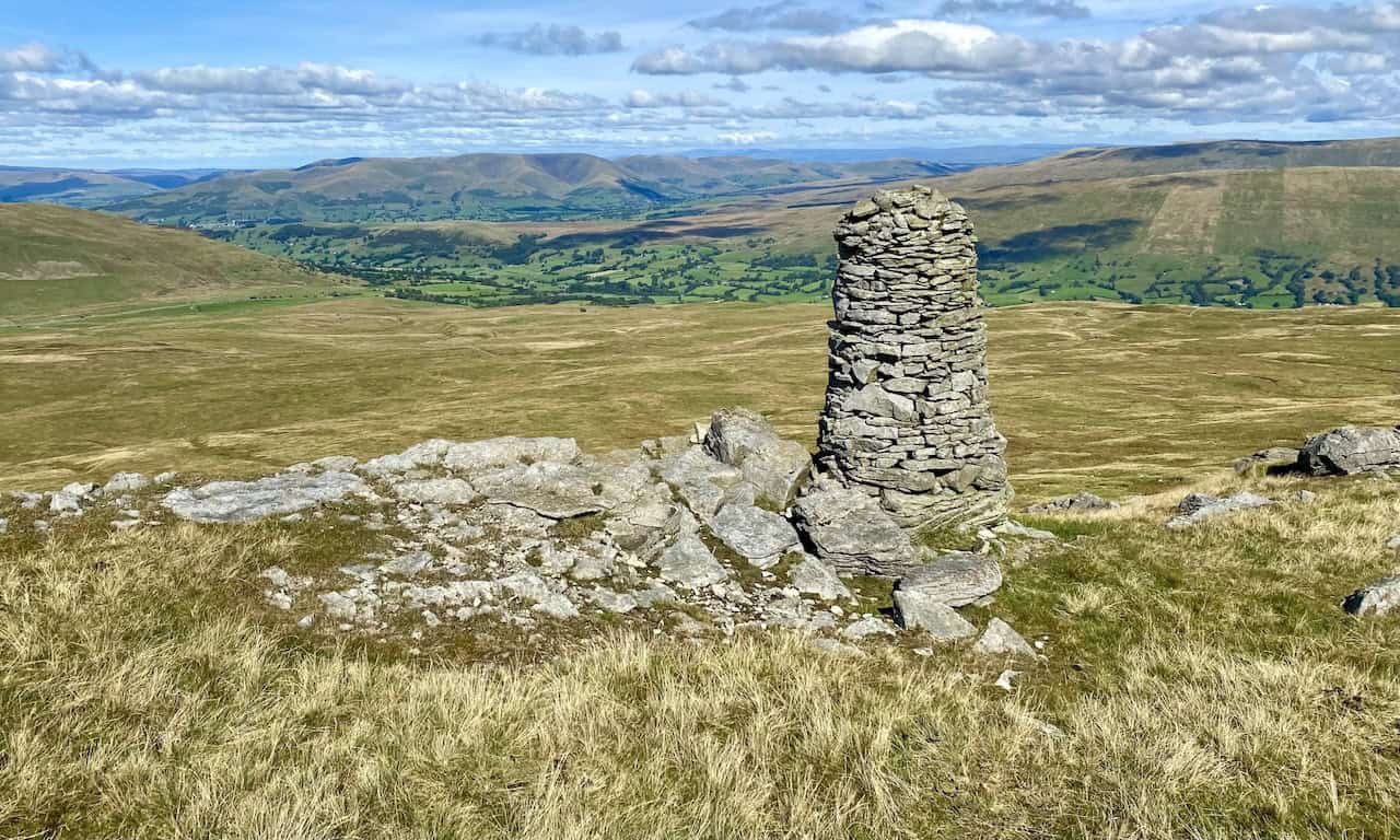 A magnificent cairn above The Crag, offering spectacular views of the Howgill Fells, surrounding countryside, and the Lake District mountains on the horizon.