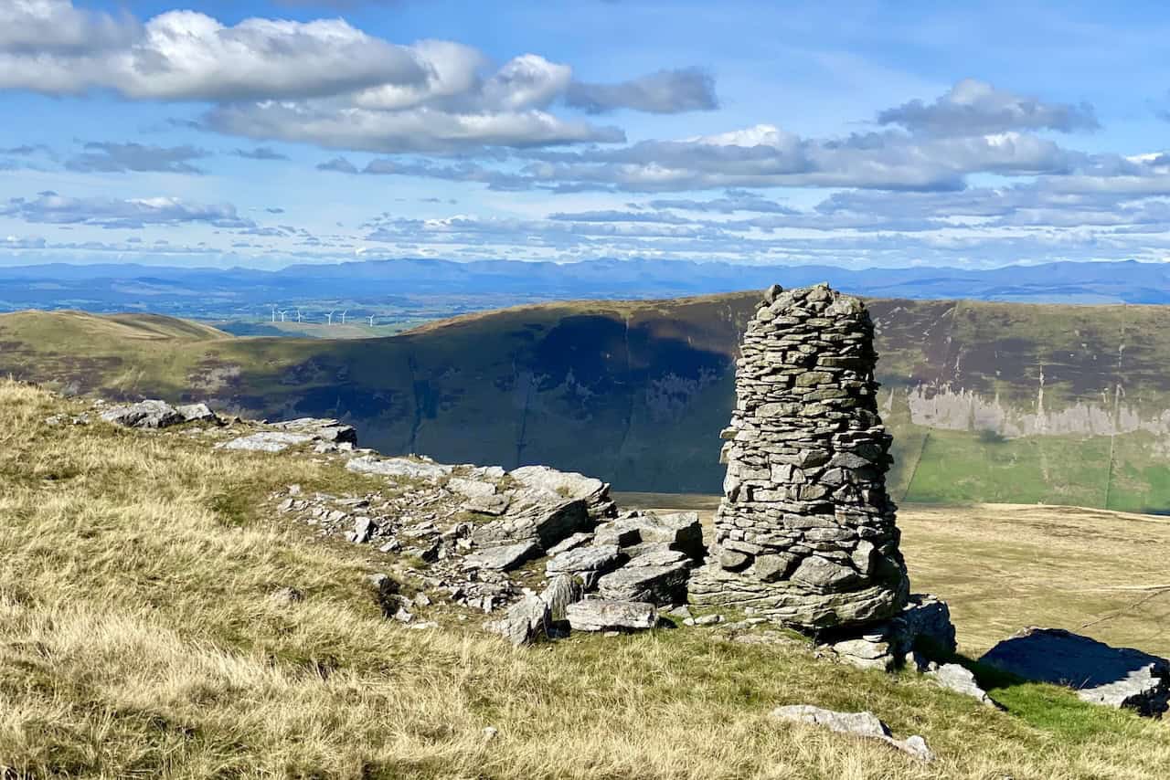 A magnificent cairn above The Crag, offering spectacular views of the Howgill Fells, surrounding countryside, and the Lake District mountains on the horizon.