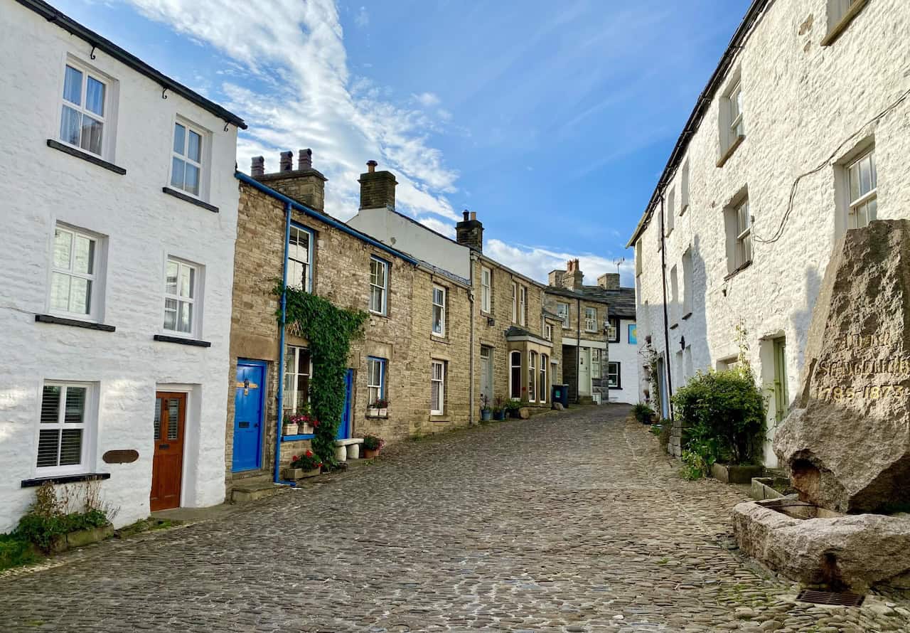 A picturesque scene of Dent village, featuring cobbled streets and charming white-walled cottages, marking the conclusion of the Great Coum walk.