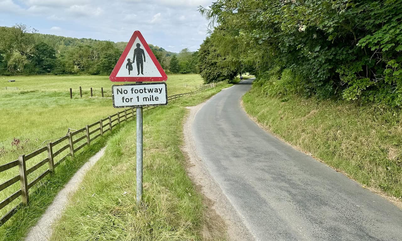 A road sign warning of no footway for one mile, with the road leading towards Rievaulx Bridge.
