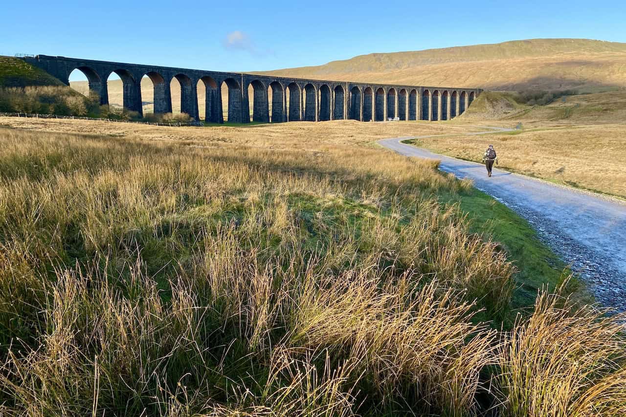 View of Ribblehead Viaduct with Whernside in the background during the Whernside circular walk, approaching the viaduct before turning right to ascend the embankment.