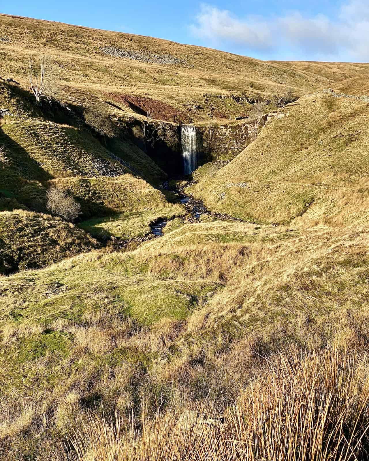 View of the waterfall created by Force Gill, seen from the Dales High Way, west of Slack Hill during the Whernside circular walk.