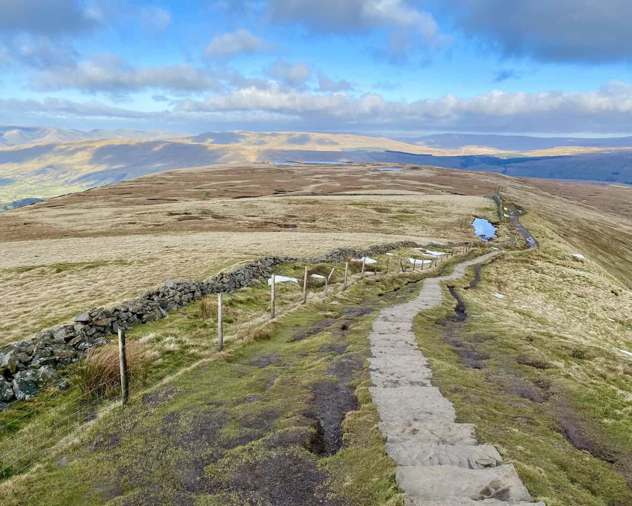 Backward view of Whernside Tarns while climbing the steps to Whernside's summit, with the Howgill Fells visible in the distance.