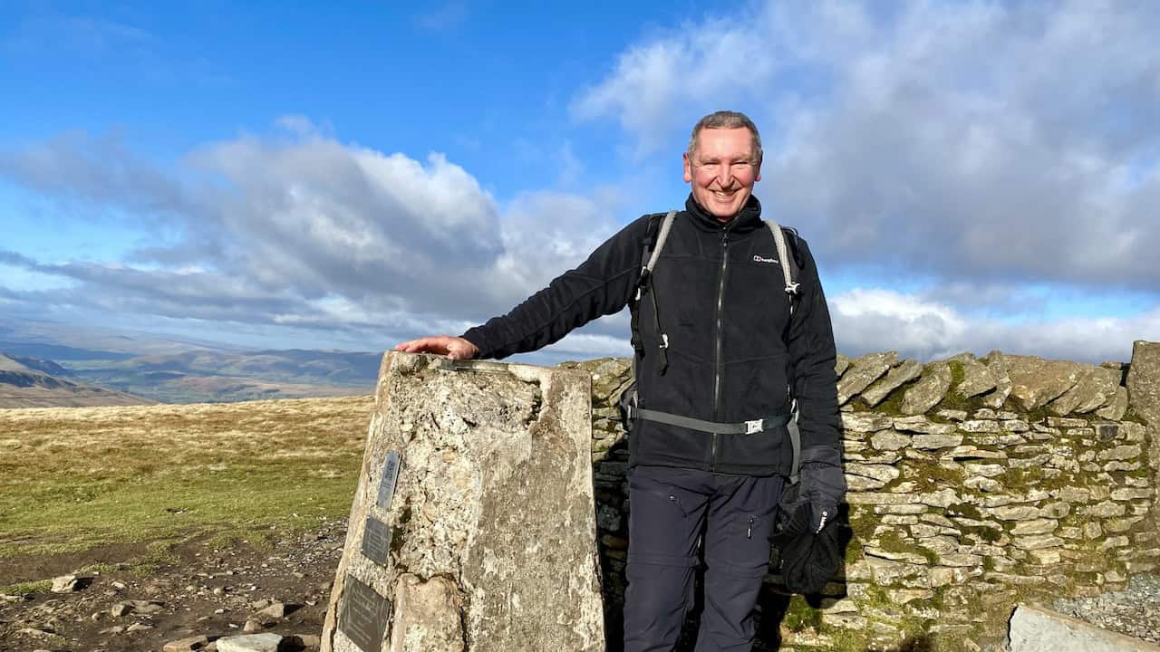 Triangulation pillar at Whernside's summit, 736 metres (2415 feet), marking the highest point of the Whernside circular walk with a list of the seven highest mountains in the Yorkshire Dales.